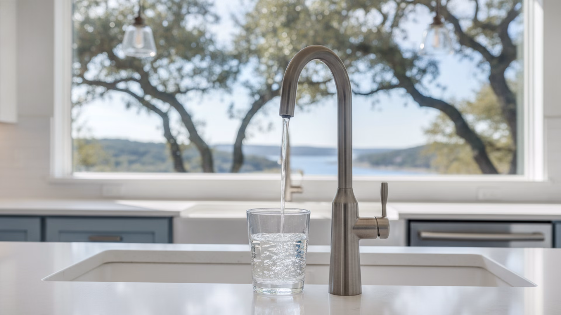 Clear stream of water pouring from a dedicated drinking-water faucet into a glass in a bright Hill Country kitchen