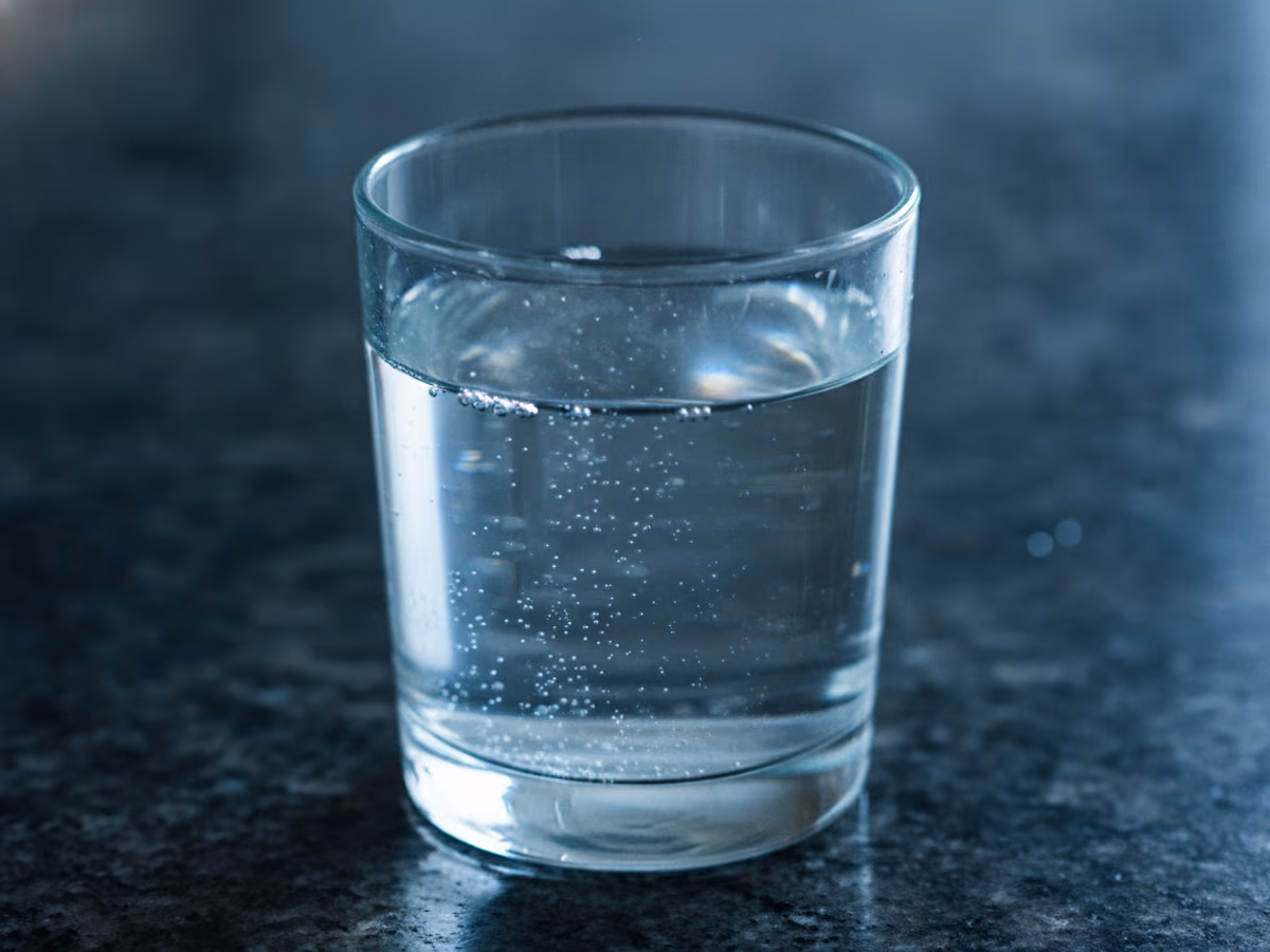 Back-lit glass of perfectly clear water on a dark counter